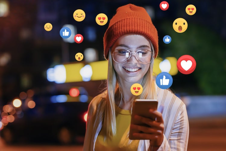 Woman smiling and using her mobile phone with reaction icons