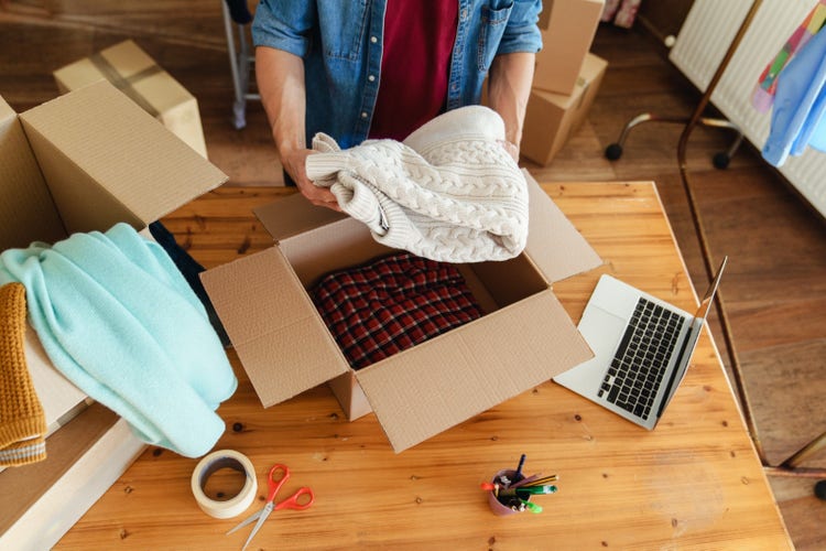 A Facebook Marketplace seller packing thrift shop items into a box to ship to a customer.