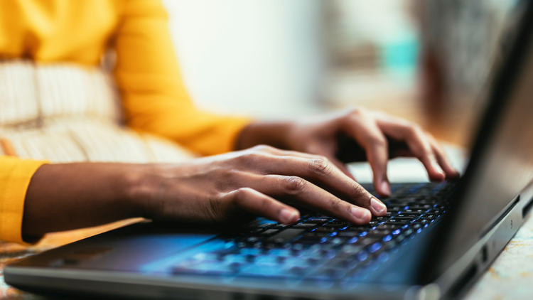 Typing Two hands type on the keyboard of a laptop.