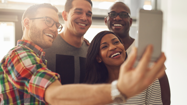 A group of four take a selfie together. There are three men and one woman.