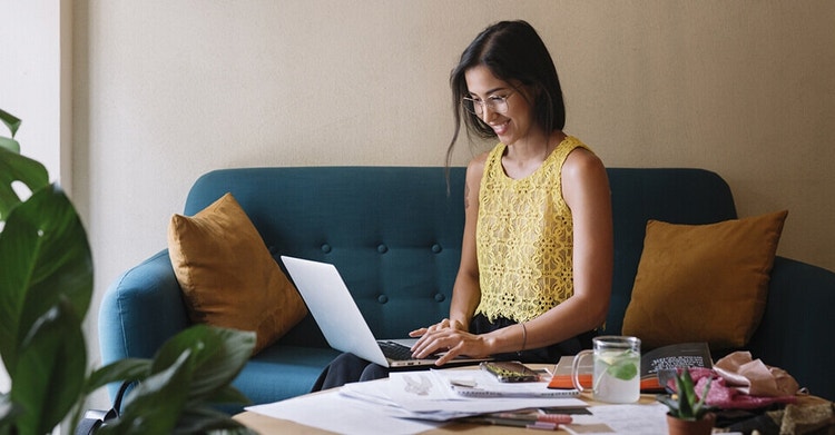 A business owner creating a business proposal on their laptop while sitting on a couch