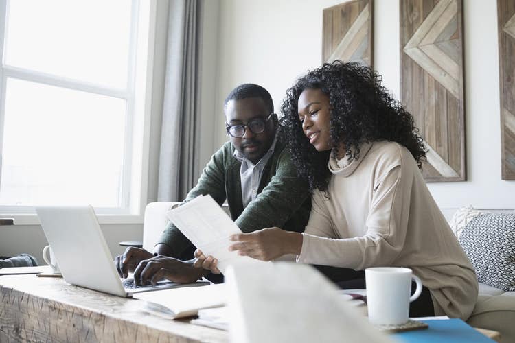 A couple sitting on a couch reviewing a paper mortgage note together