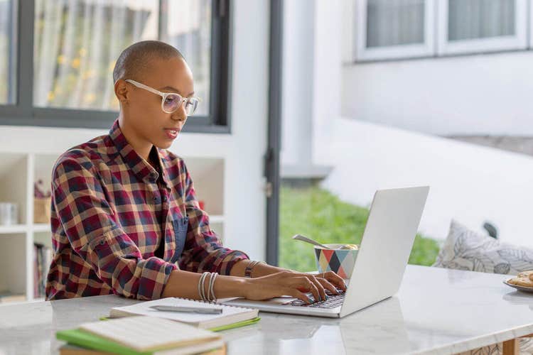 A business owner sitting at a desk writing up a business proposal on their laptop