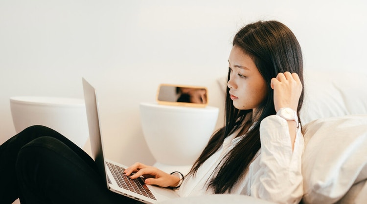 A potential tenant reviewing a house rental agreement on a laptop while sitting on a couch