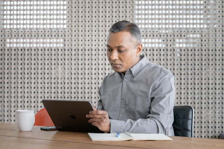 A photo of a person sitting at a table in a conference room and working on a laptop computer.