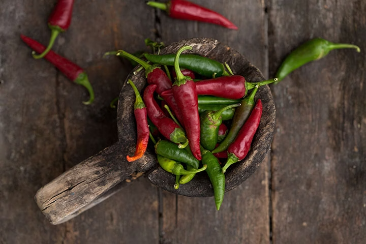 Piments rouges et verts devant arrière-plan de bois