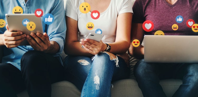 des personnes regardent leurs écrans de réseaux sociaux d'où s'échappent des emoji