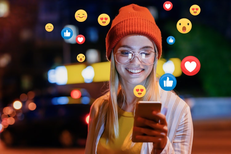 Une femme regarde son écran d'où sortent des emoji