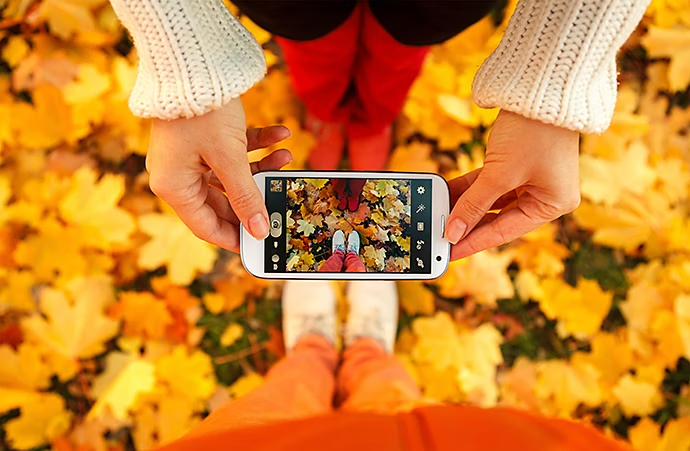 Hipsters photographiant des feuilles d’automne et leurs chaussures.