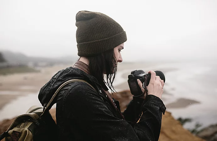 Photographe debout près du rivage, observant son réflex numérique