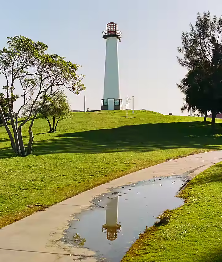 Phare perché sur une colline verdoyante, se reflétant dans une flaque d’eau devant lui