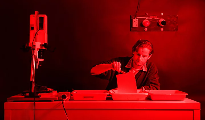 A photo of a person developing a Kirlian photo in a photography darkroom.