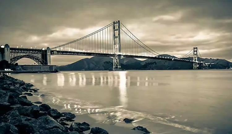 Photo sépia d’un pont au-dessus d’une eau calme la nuit