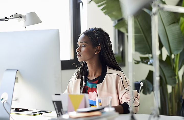 Personne assise à son bureau en train d’utiliser un ordinateur