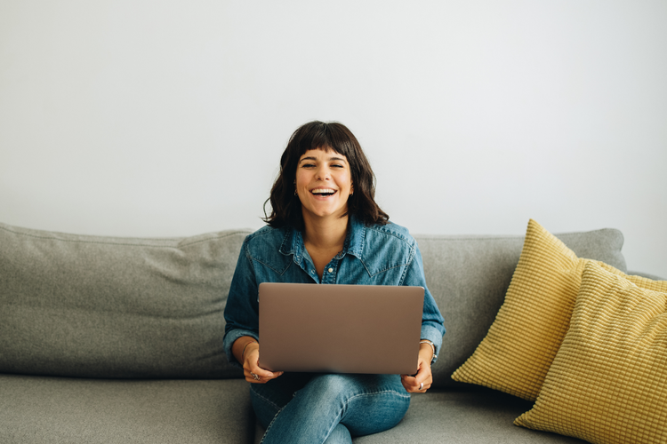 A person sitting on a couch with a computer Description automatically generated