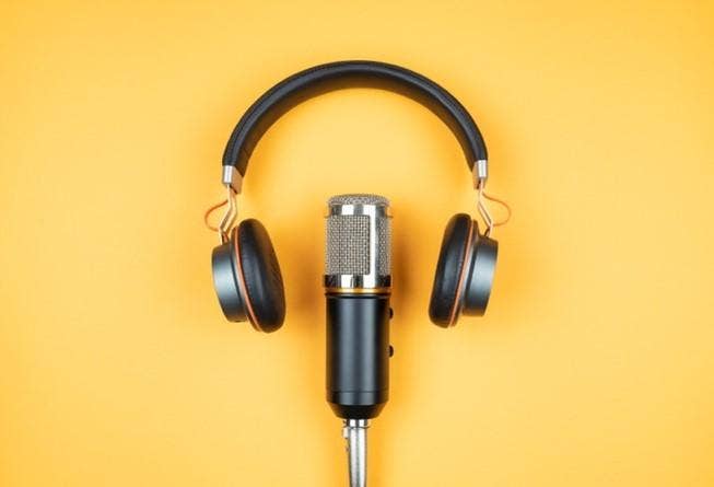 A podcast microphone and a pair of headphones against a yellow background