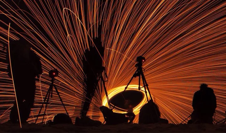 Multiple cameras pointing at a spiraling light at nighttime to create a light painting