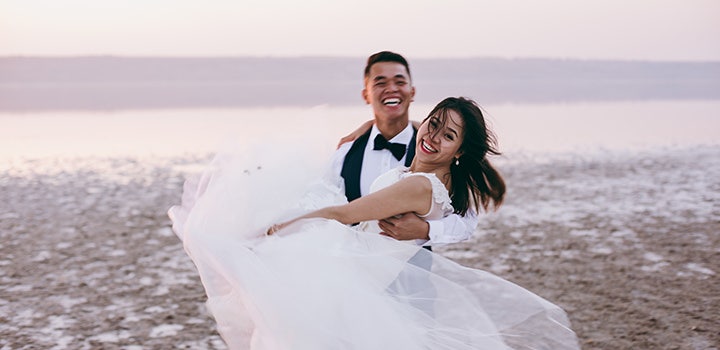 Bride and groom smiling and posing on the beach.