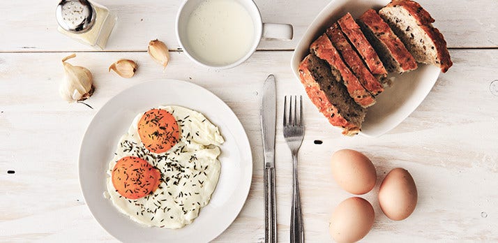 Simple food photograph of eggs over easy with milk and bread