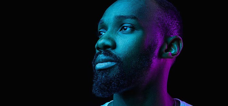 Blue and purple light illuminate the headshot of a man in an example of low-key lighting