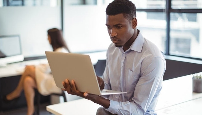 A mortgage lender reviewing digital documents on a laptop they are holding up