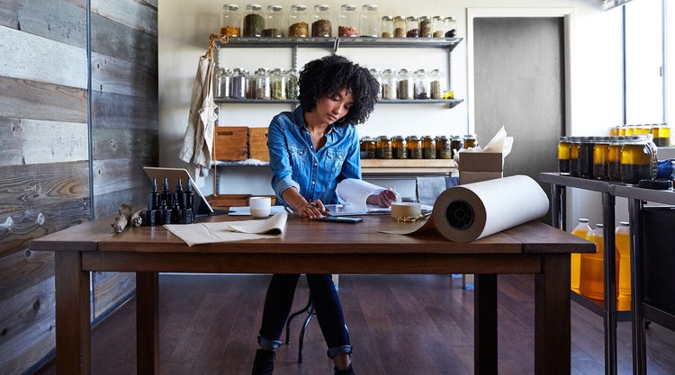 A small business owner does paperwork at a table