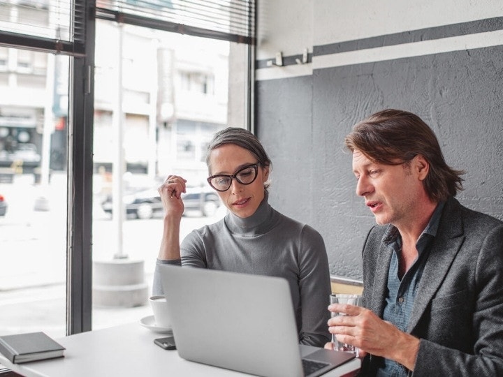 Two people reviewing a digital mortgage before signing with Acrobat Sign while seated at a window desk