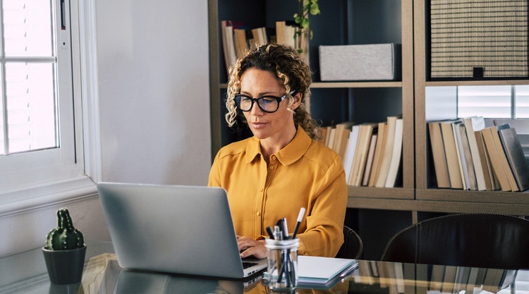 A person sitting in their office working on an affidavit on their laptop