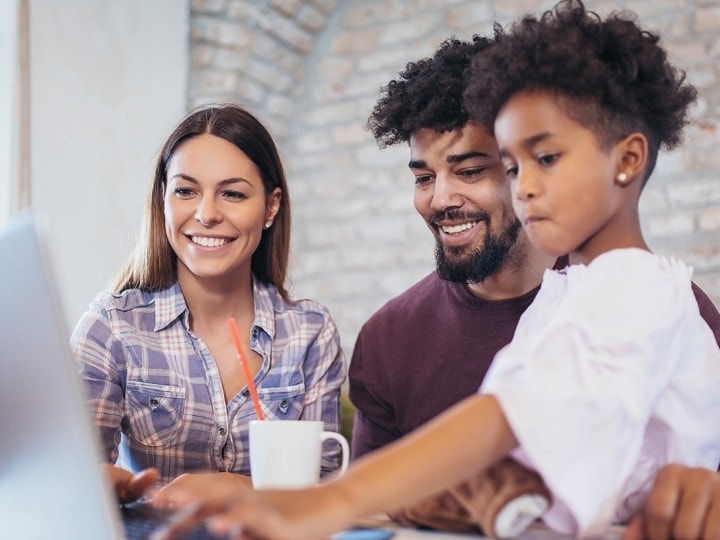 Parents looking over a digital school form with their child at the dining table before signing it with Acrobat Sign