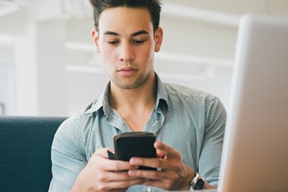 A lender tapping out a message on their cell phone while sitting at their desk.