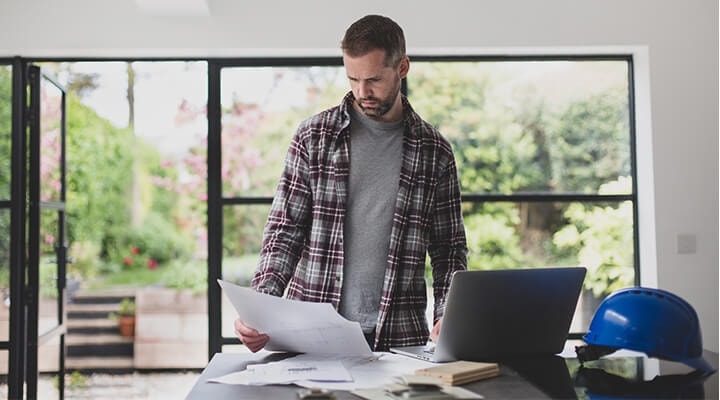 A roof contractor standing at a desk reviewing paperwork