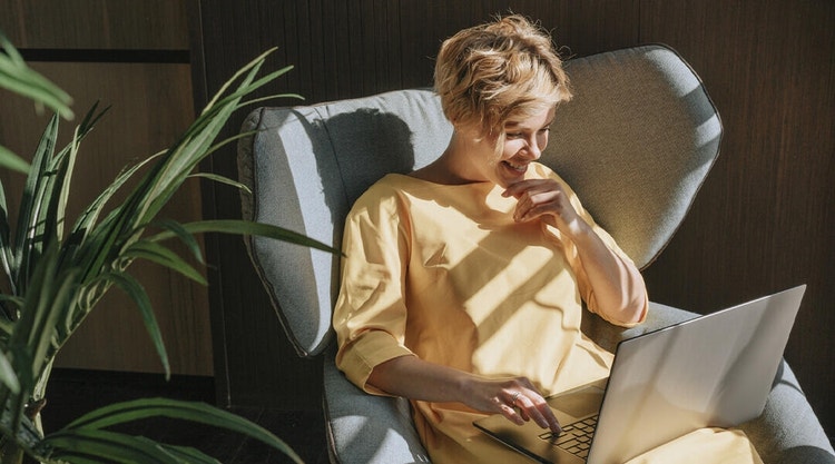 A business owner sitting on a chair reviewing a loan agreement with their laptop