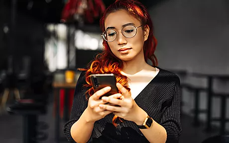 Woman checking mobile phone for latest Adobe Stock blog