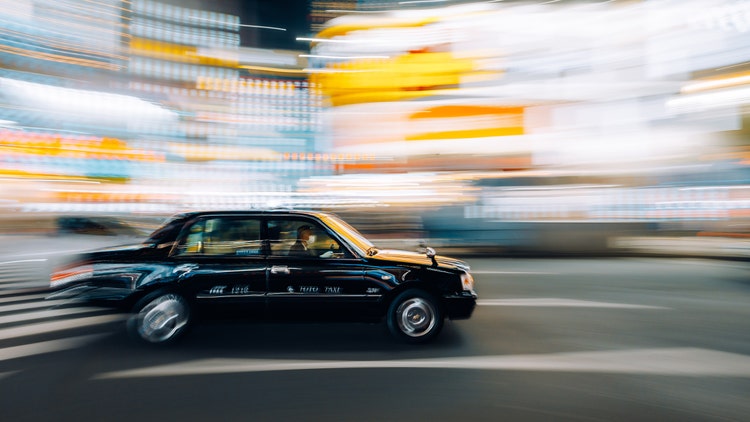 Light trails and motion blur of a black taxi on a street