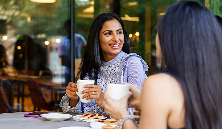 Two actors sitting at a table drinking coffee for a commercial