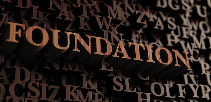 Grafis tulisan kayu mengeja kata "foundation."