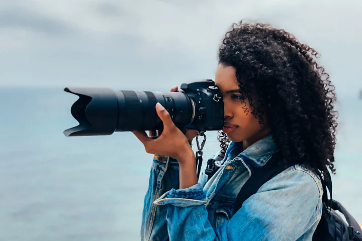 A photographer taking a photo with their camera, which has a telephoto lens