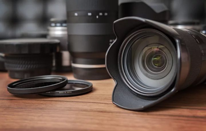 Various camera lenses laid out on a wooden table which demonstrates lens photography