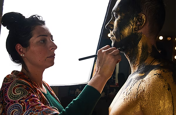 Makeup artist applies black and gold SFX makeup to a subject