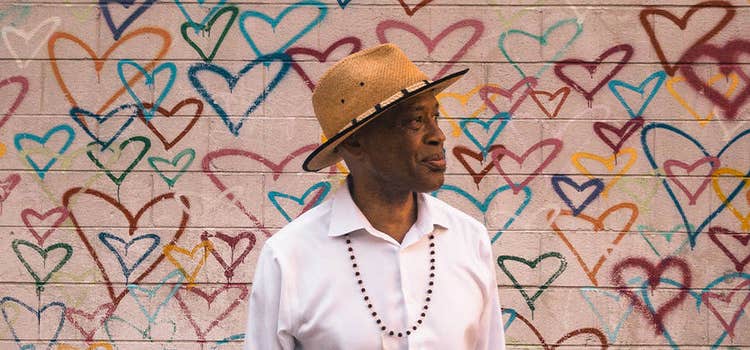 Inspirational headshot photo of a man in front of a wall of graffiti hearts.