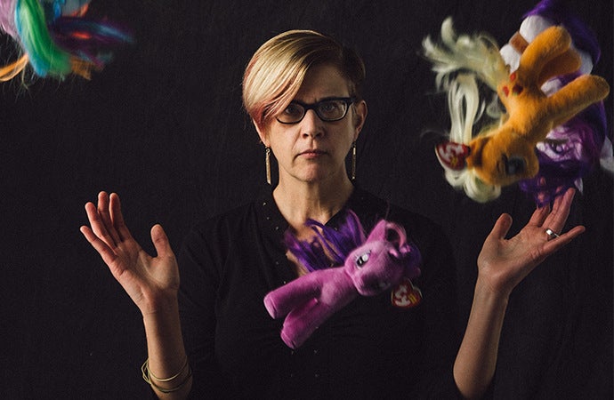 Creative headshot of a woman and falling stuffed ponies.