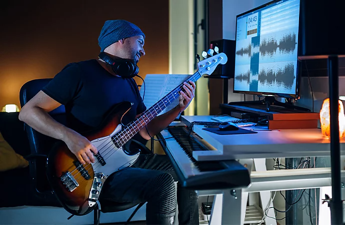 A musician recording bass using a tube compressor.