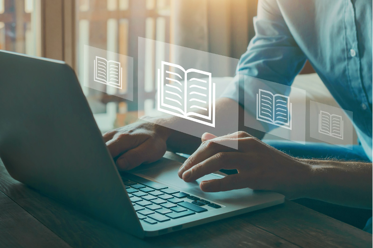 A person typing on laptop with digital books emerging in foreground in various styles.