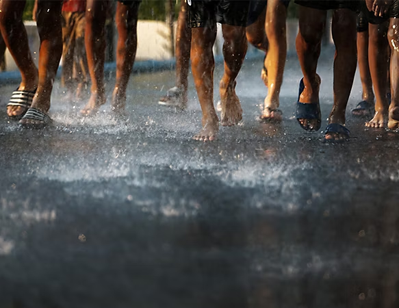 A photo of people's feet walking in the rain.