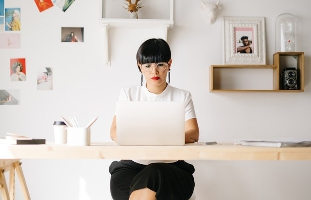 A photo of a person sitting at a desk in an office and using a laptop computer.