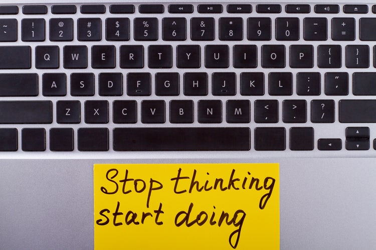 Computer portatile con un post-it giallo su cui è scritto "Stop thinking, start doing