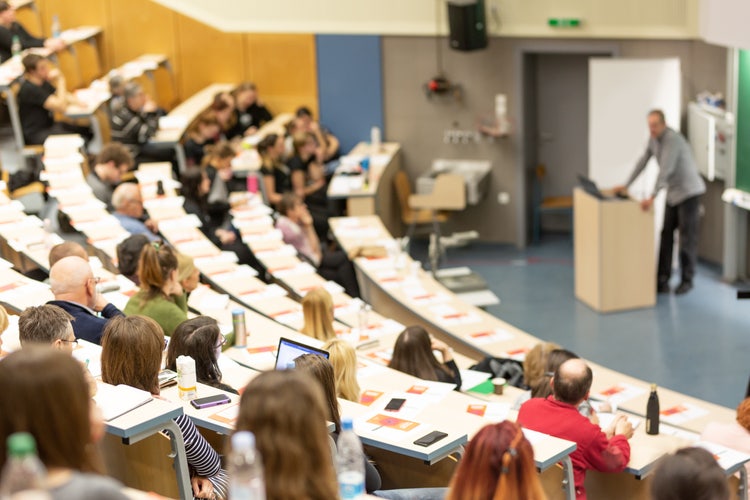 Aula universitaria a gradoni con studenti e docente