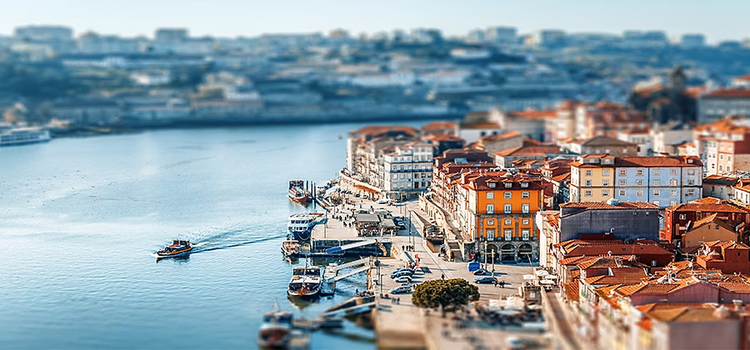 A tilt-shift photo of buildings along a riverfront