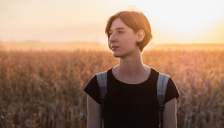 backlit-portrait-of-a-woman-in-sunset-female-person-standing-in-evening-sunlight-at-a-field