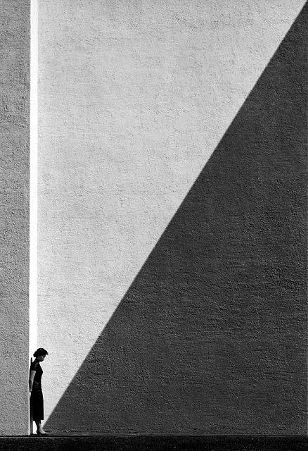 Black-and-white photo of person standing against wall